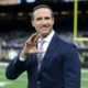 Drew Brees in a suit and tie holding his hand up